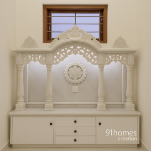 White marble mandir with carved arch and lotus motif design.